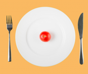 Une assiette vide avec une unique tomate cerise au centre, symbolisant la restriction cognitive, où les choix alimentaires sont limités ou contraints
